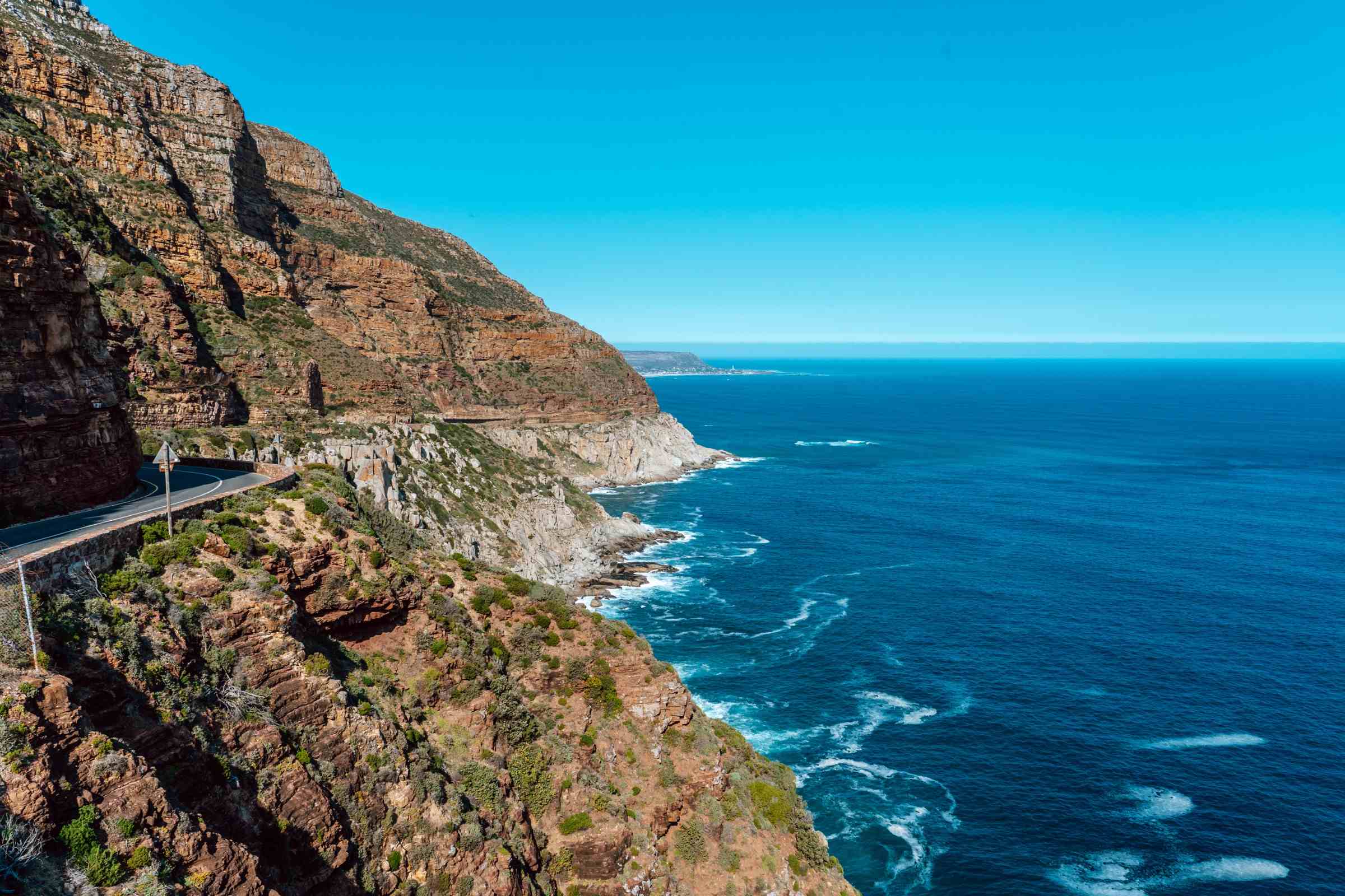 Скальная дорога Chapman's Peak изгибается над синим Атлантическим океаном под ясным дневным небом