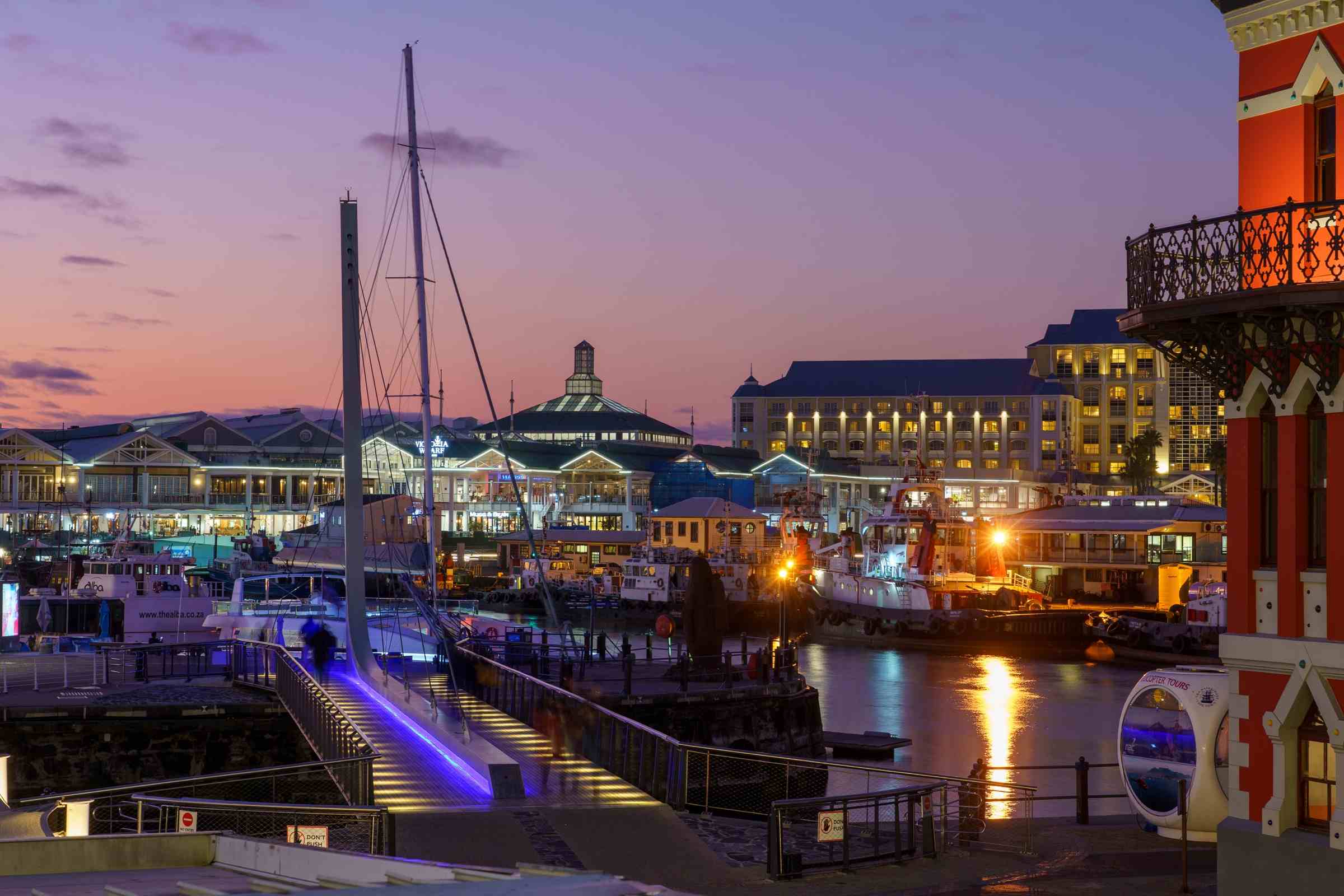 Яхты, портовые суда и здания V&A Waterfront в фиолетовом свете после заката